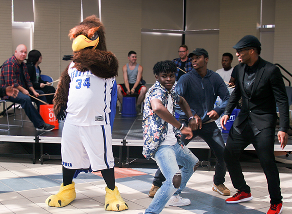 Students dancing with Hawkster mascot in front of band playing